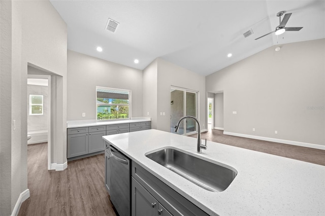 kitchen featuring stainless steel dishwasher, sink, vaulted ceiling, gray cabinets, and dark hardwood / wood-style flooring