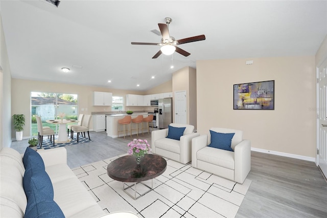 living room with light hardwood / wood-style floors, lofted ceiling, and ceiling fan