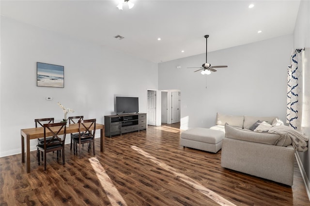 living room with a towering ceiling, ceiling fan, and dark hardwood / wood-style flooring