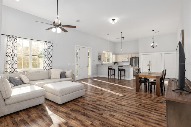 living room featuring ceiling fan with notable chandelier, a high ceiling, and dark hardwood / wood-style flooring