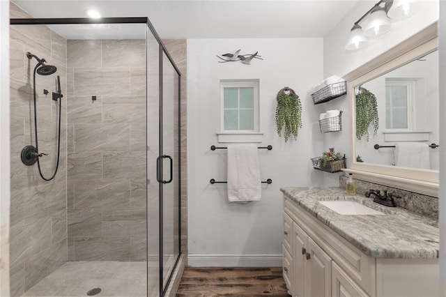 bathroom with a shower with shower door, hardwood / wood-style floors, and vanity