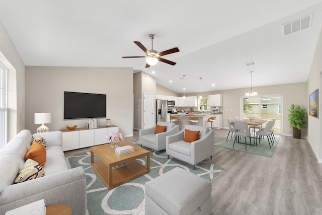 living room with ceiling fan, lofted ceiling, and light wood-type flooring