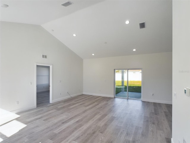 empty room with high vaulted ceiling and light hardwood / wood-style floors