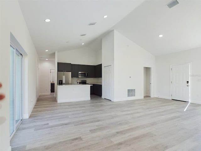 kitchen with light hardwood / wood-style flooring, a kitchen island, high vaulted ceiling, and appliances with stainless steel finishes