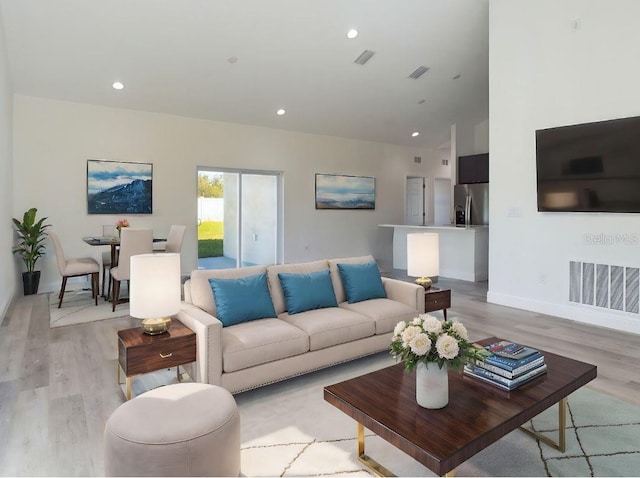 living room featuring light hardwood / wood-style flooring and high vaulted ceiling