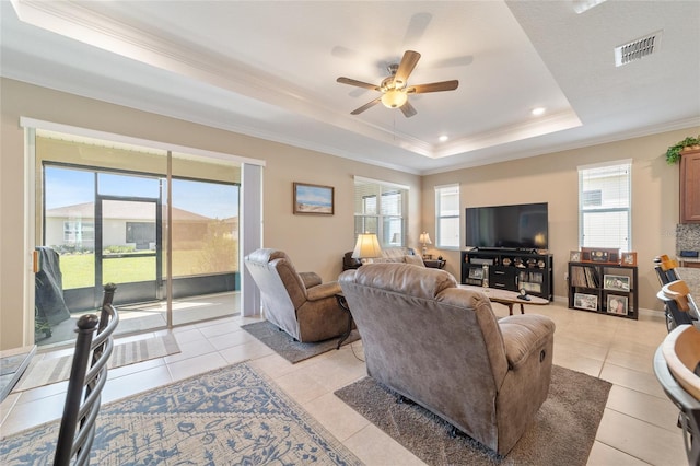 living room with ornamental molding, light tile patterned flooring, ceiling fan, and a raised ceiling