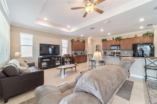 tiled living room featuring crown molding, ceiling fan, plenty of natural light, and a raised ceiling