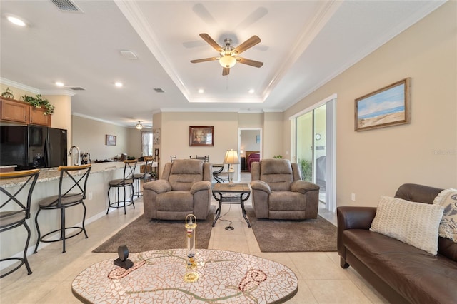 tiled living room featuring crown molding and a raised ceiling