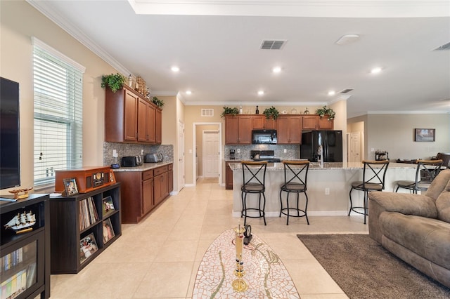 kitchen with tasteful backsplash, black appliances, a kitchen breakfast bar, ornamental molding, and light tile patterned floors