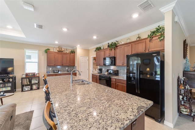 kitchen featuring a spacious island, decorative backsplash, sink, black appliances, and crown molding