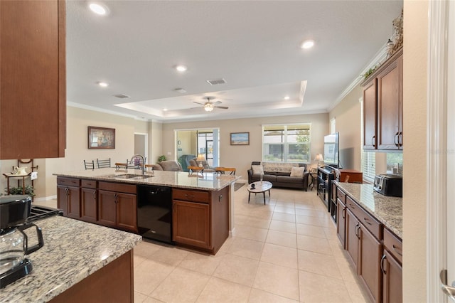 kitchen featuring a center island with sink, light stone counters, a raised ceiling, dishwasher, and sink