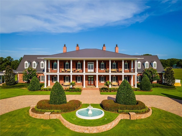 back of property featuring a lawn and a balcony