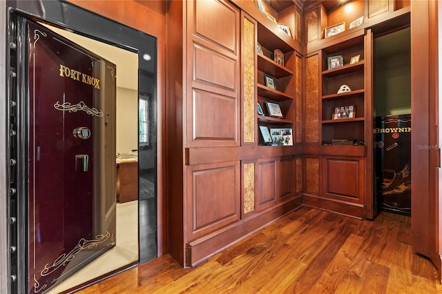 hall featuring built in shelves and dark wood-type flooring