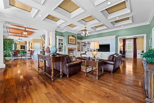 living room with an inviting chandelier, coffered ceiling, built in shelves, ornamental molding, and beam ceiling