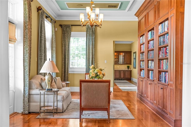 living area with a chandelier, light hardwood / wood-style floors, and crown molding