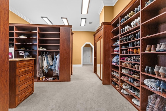 spacious closet featuring visible vents, arched walkways, and light colored carpet