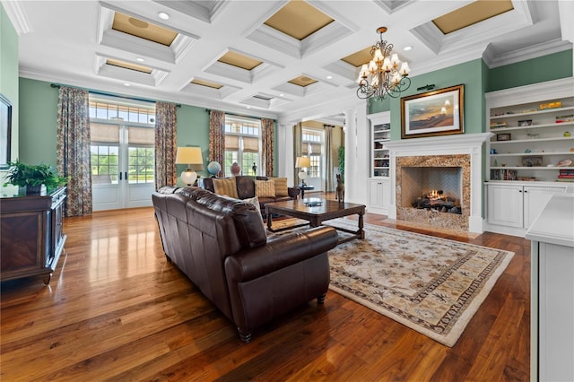 living room with built in shelves, french doors, coffered ceiling, a premium fireplace, and crown molding