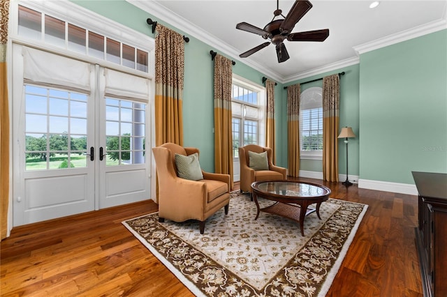 living area featuring crown molding, baseboards, and wood finished floors