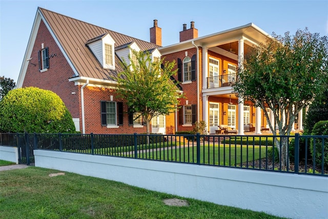 view of front of property with a standing seam roof, a front yard, and brick siding