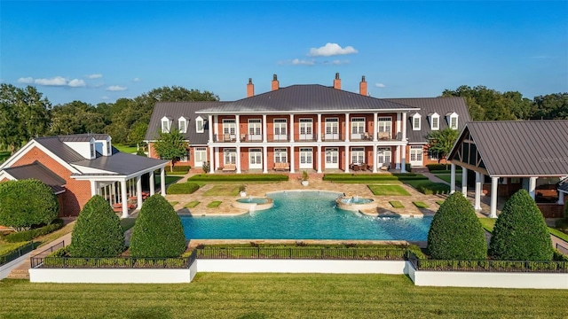 rear view of house with an outdoor pool, metal roof, a patio, and a yard