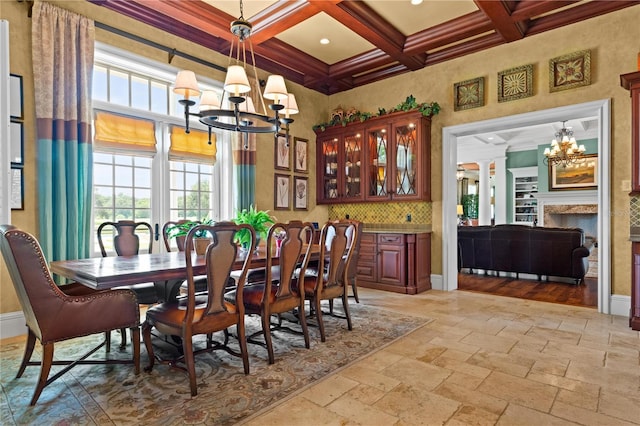 dining area featuring baseboards, a chandelier, coffered ceiling, and stone tile flooring