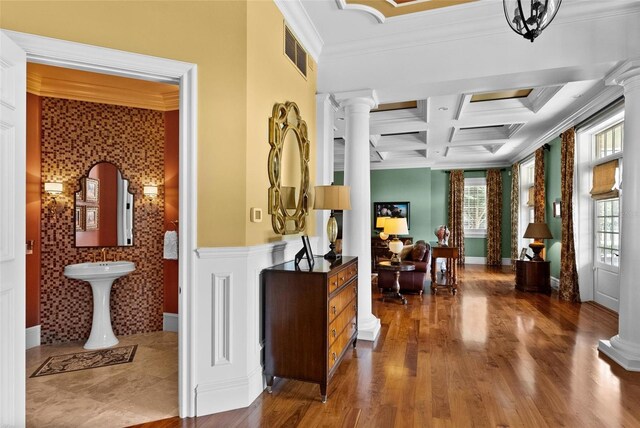 interior space with crown molding, visible vents, wood finished floors, coffered ceiling, and ornate columns