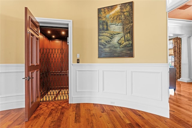 interior space with a wainscoted wall, wood finished floors, visible vents, and a decorative wall