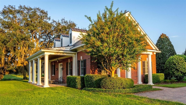 view of side of home featuring a standing seam roof, brick siding, a lawn, and metal roof