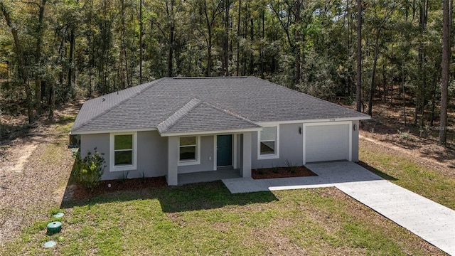 ranch-style house with an attached garage, driveway, roof with shingles, stucco siding, and a front yard