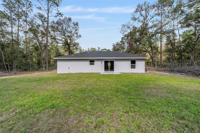 rear view of property with a lawn and stucco siding