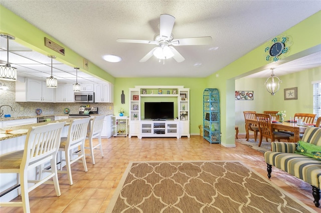 living room featuring a textured ceiling and ceiling fan with notable chandelier