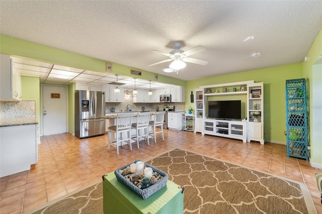 tiled living room featuring ceiling fan and a textured ceiling