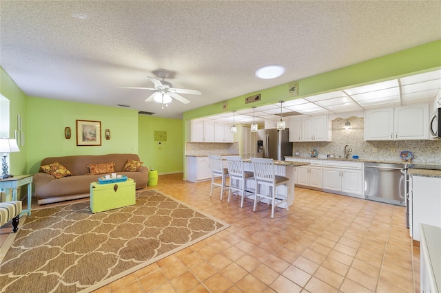 living room featuring ceiling fan, light tile patterned flooring, a textured ceiling, and sink