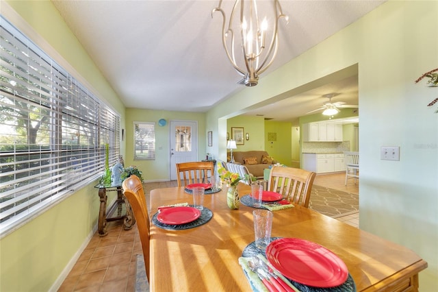 tiled dining area with a textured ceiling and ceiling fan with notable chandelier