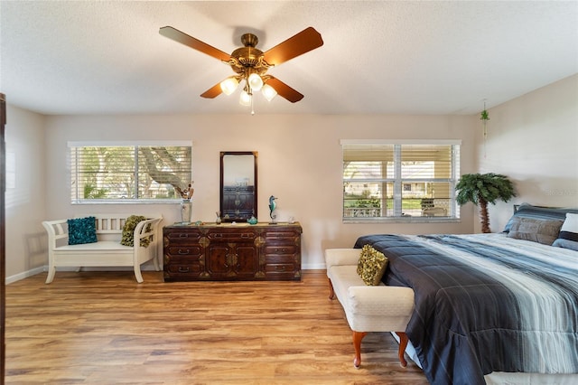 bedroom with a textured ceiling, multiple windows, light hardwood / wood-style floors, and ceiling fan