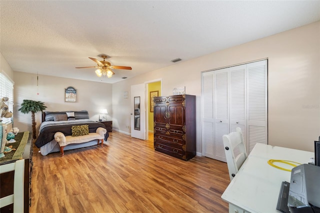 bedroom with a closet, a textured ceiling, wood-type flooring, and ceiling fan