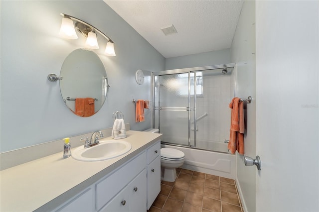 full bathroom featuring bath / shower combo with glass door, a textured ceiling, toilet, vanity, and tile patterned flooring