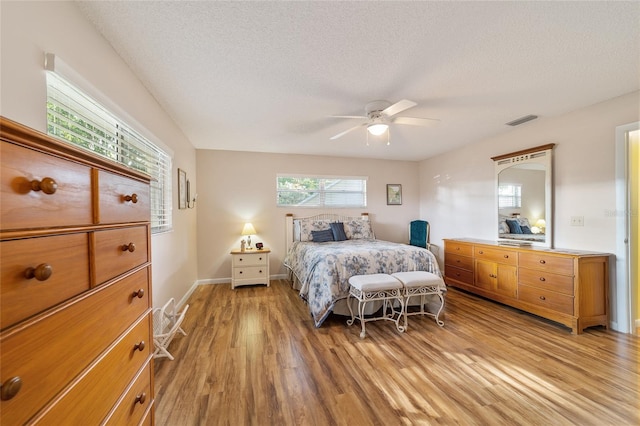 bedroom with ceiling fan, a textured ceiling, and light hardwood / wood-style flooring