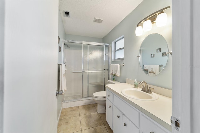 bathroom featuring a textured ceiling, walk in shower, toilet, vanity, and tile patterned flooring