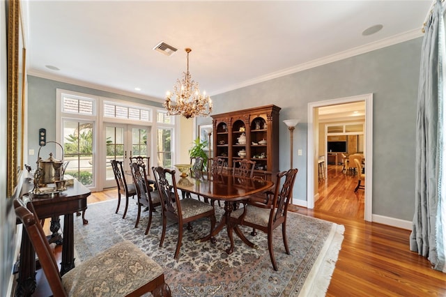 dining area featuring hardwood / wood-style floors, a notable chandelier, and crown molding