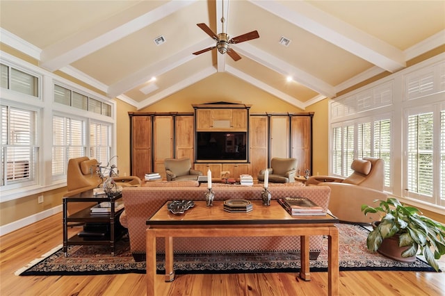 living room featuring wood-type flooring, beamed ceiling, a wealth of natural light, and a barn door