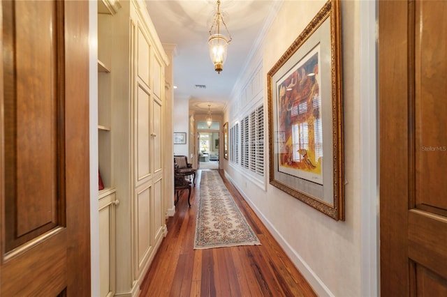 hallway featuring ornamental molding, hardwood / wood-style flooring, and built in features