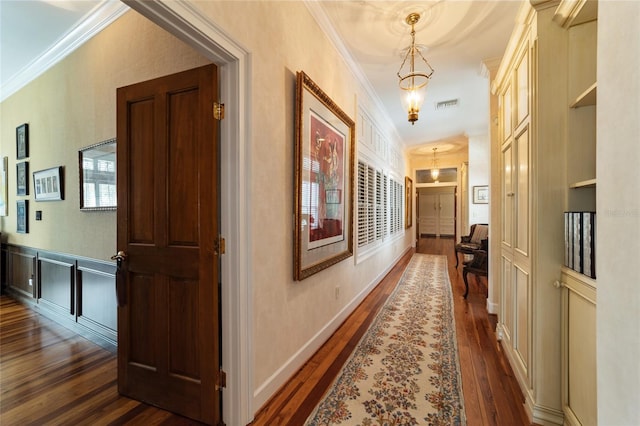 corridor with crown molding, built in features, dark hardwood / wood-style flooring, and an inviting chandelier