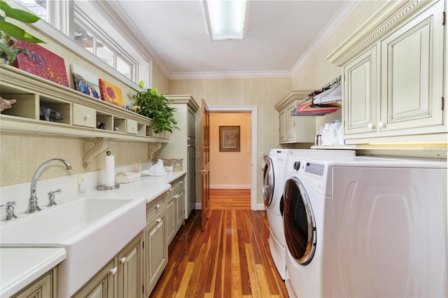 laundry room with cabinets, dark hardwood / wood-style flooring, washing machine and dryer, crown molding, and sink