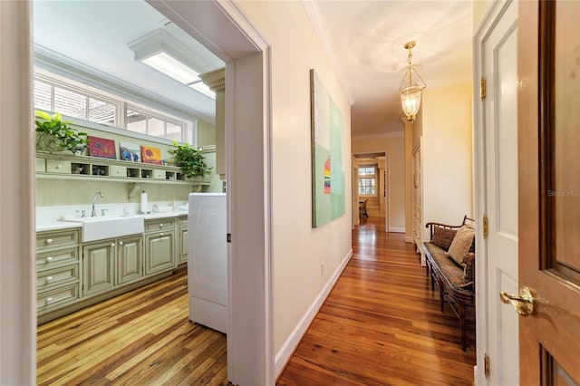 hallway featuring light hardwood / wood-style floors, crown molding, sink, and washer / dryer