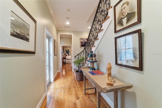 hallway featuring light hardwood / wood-style floors, crown molding, and a wealth of natural light