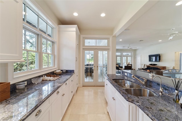 kitchen with ceiling fan, white cabinetry, dark stone countertops, french doors, and sink