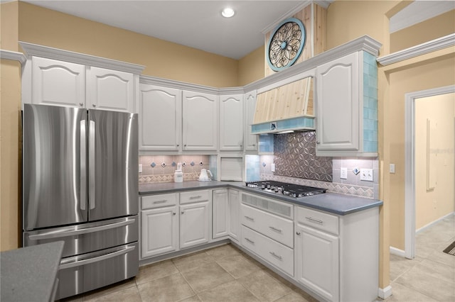 kitchen with dark countertops, backsplash, light tile patterned floors, white cabinets, and stainless steel appliances