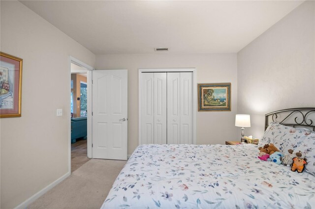 bedroom with light colored carpet, visible vents, a closet, and baseboards