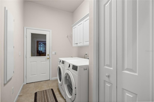 clothes washing area with light tile patterned floors, cabinet space, baseboards, and washing machine and clothes dryer